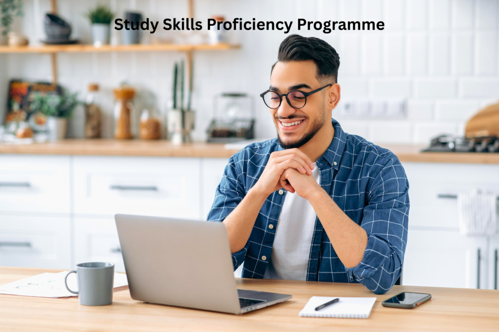 A smiling young man with glasses using a laptop at a kitchen table, with text overlay reading Study Skills Proficiency Programme.