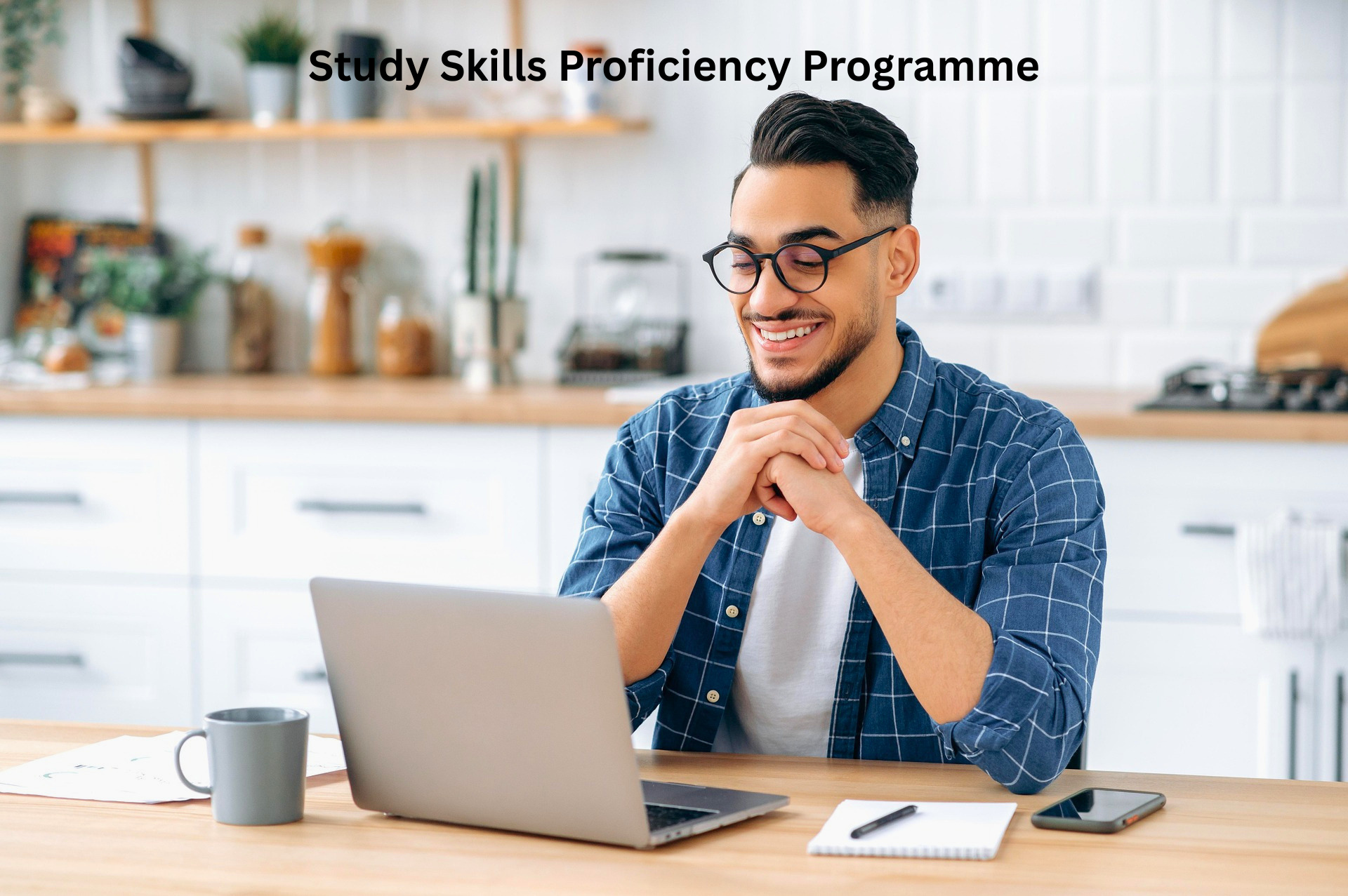 A smiling young man with glasses using a laptop at a kitchen table, with text overlay reading Study Skills Proficiency Programme.