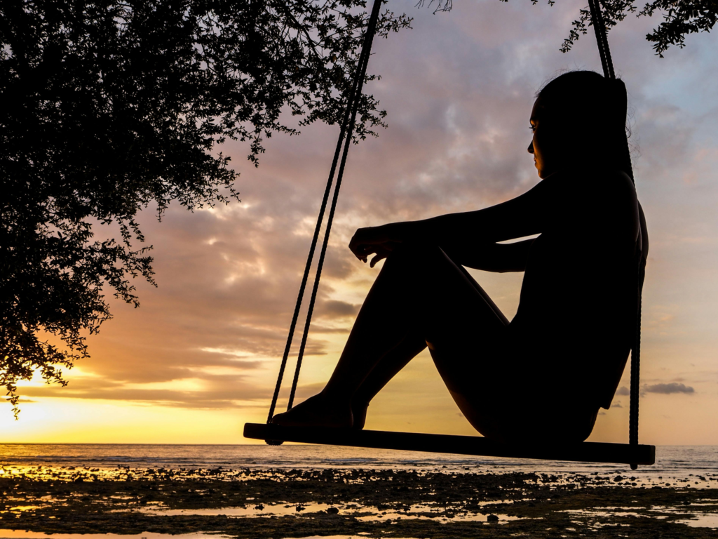 A silhouette of a person on a swing at sunset illustrating work-life balance for entrepreneurs