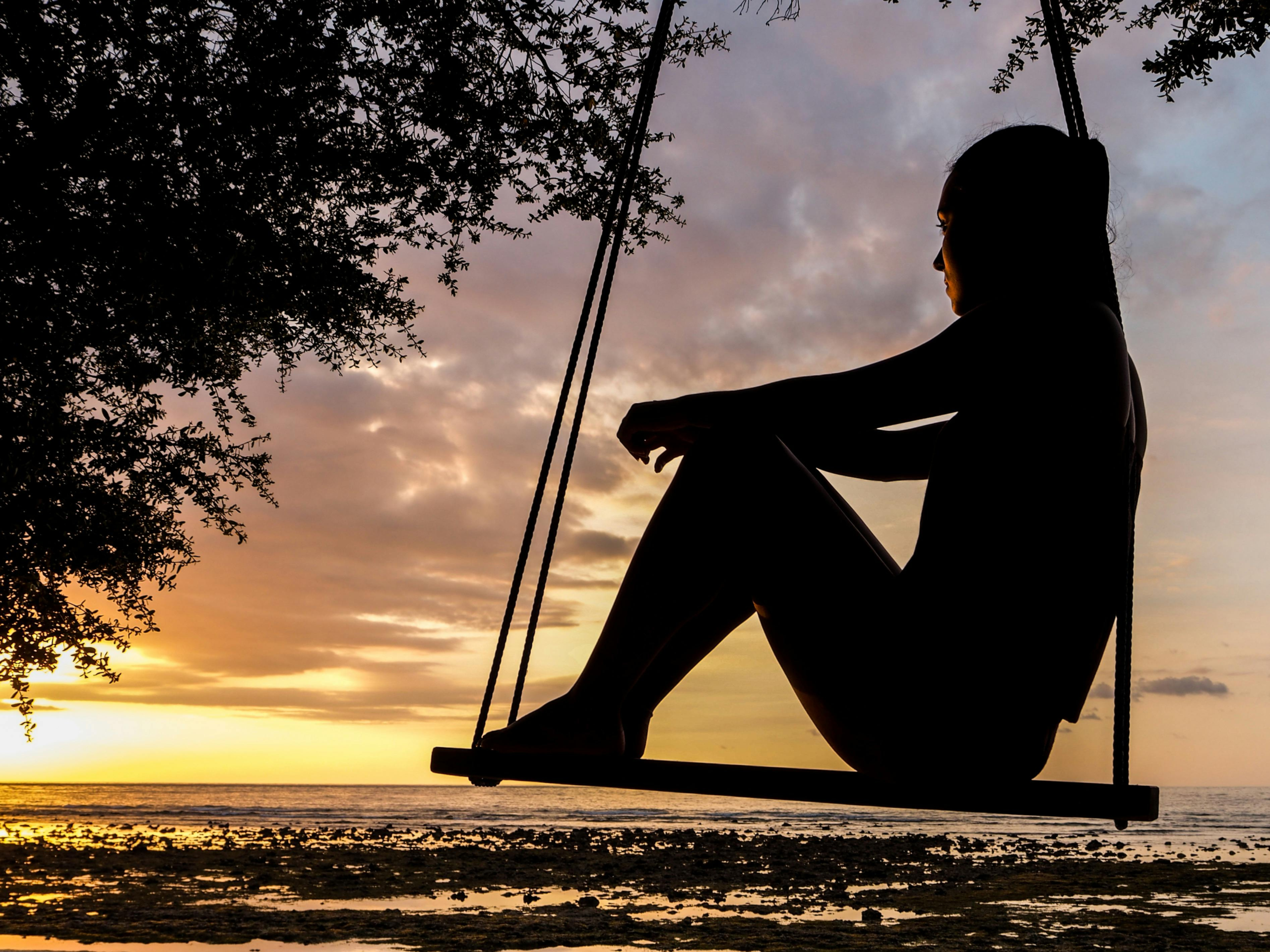 A silhouette of a person on a swing at sunset illustrating work-life balance for entrepreneurs